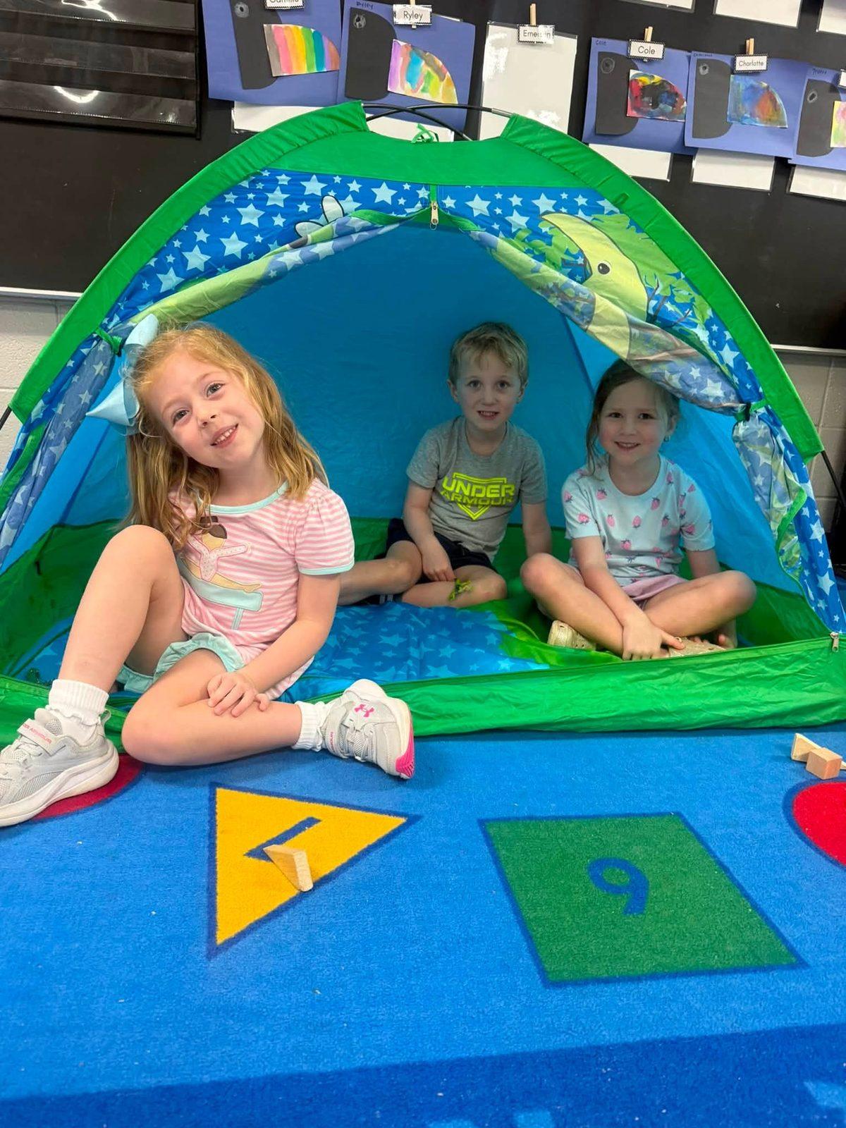 K4 students smiling inside a classroom camping tent