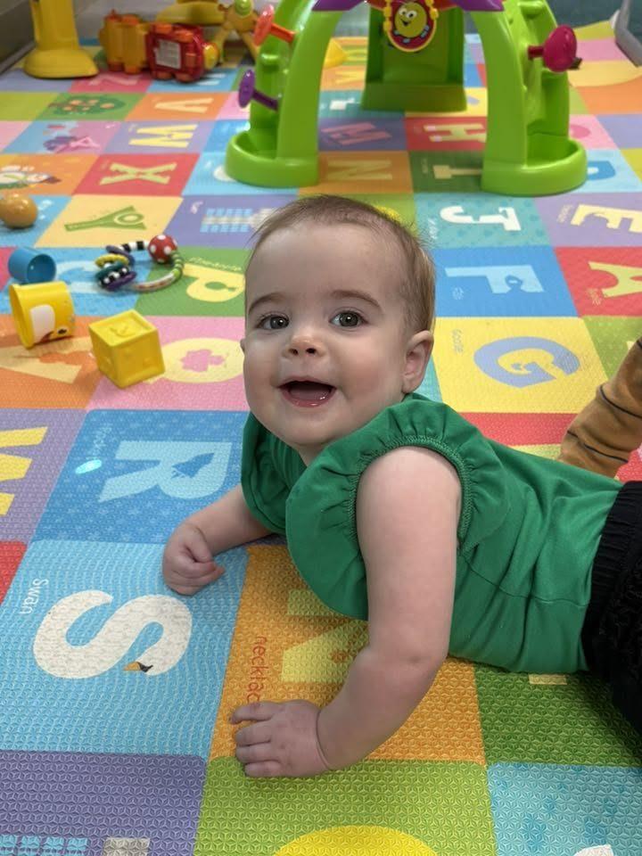 Smiling baby doing tummy time in the KCCDC nursery
