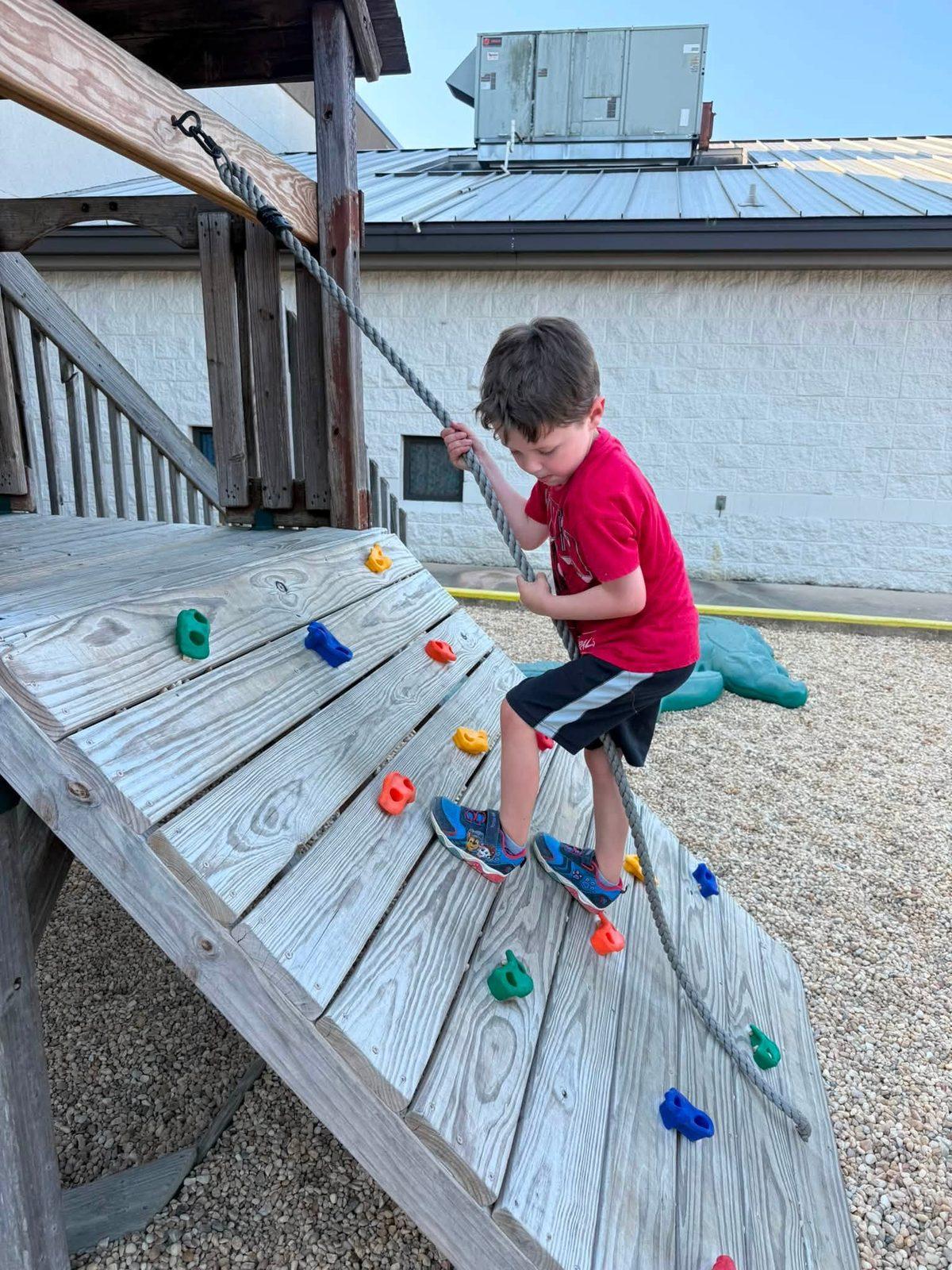 Boy climbing the playground rock wall