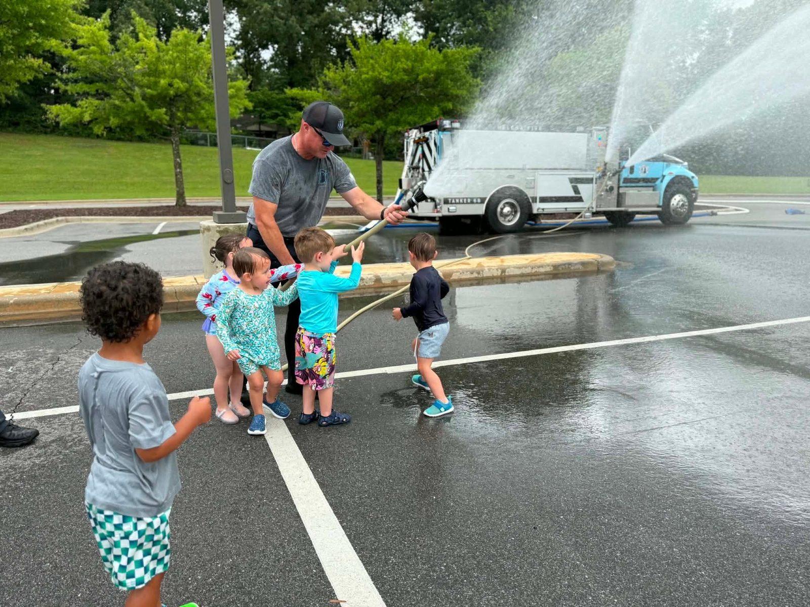 Children playing in a pop-up splash pad from a fire truck