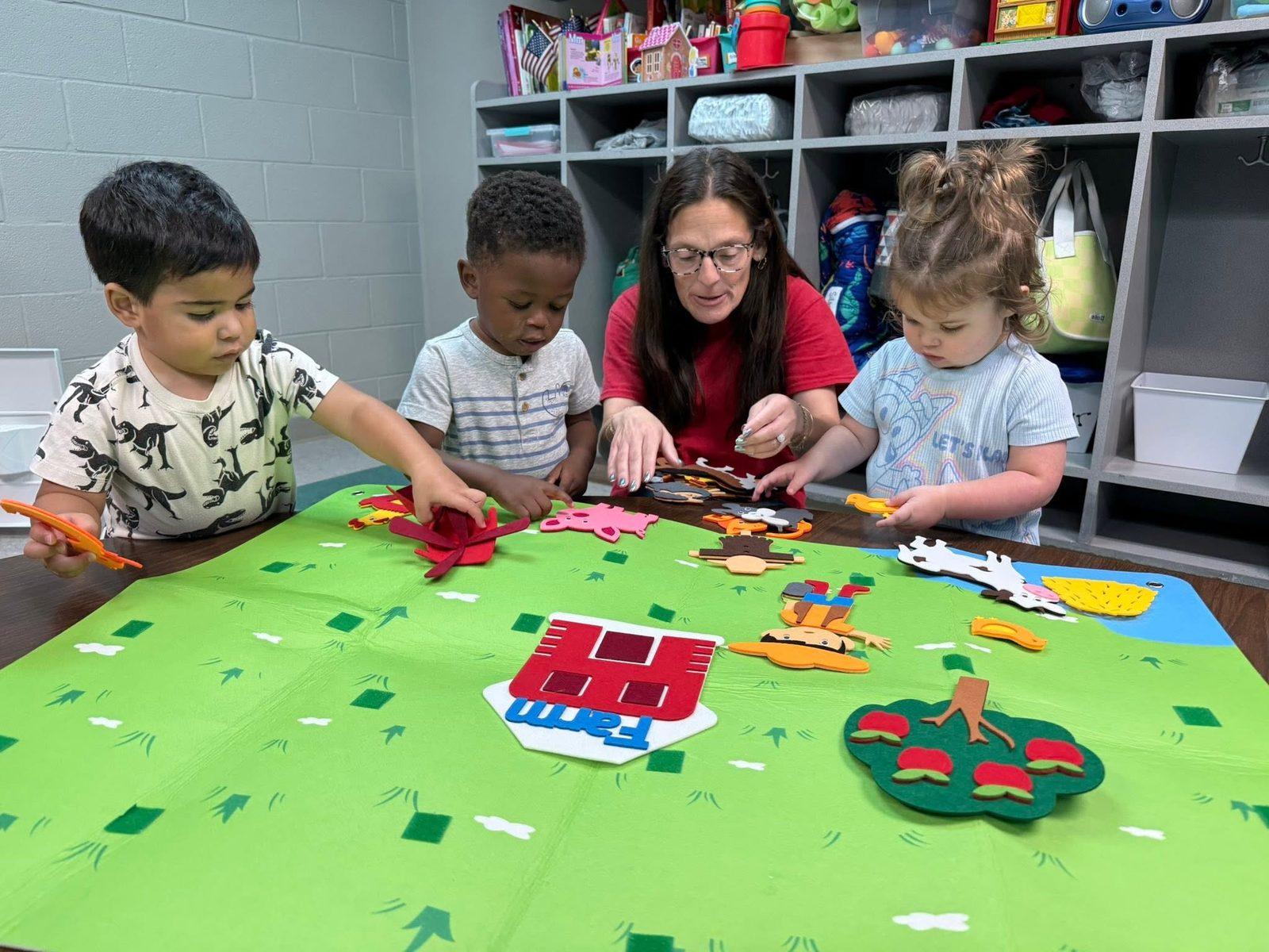 KCCDC teacher playing at a felt board table with toddlers