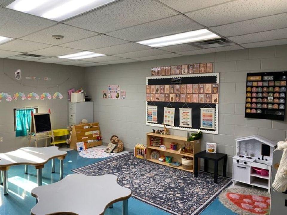 A KCCDC classroom with small tables, cubbies, and a play kitchen