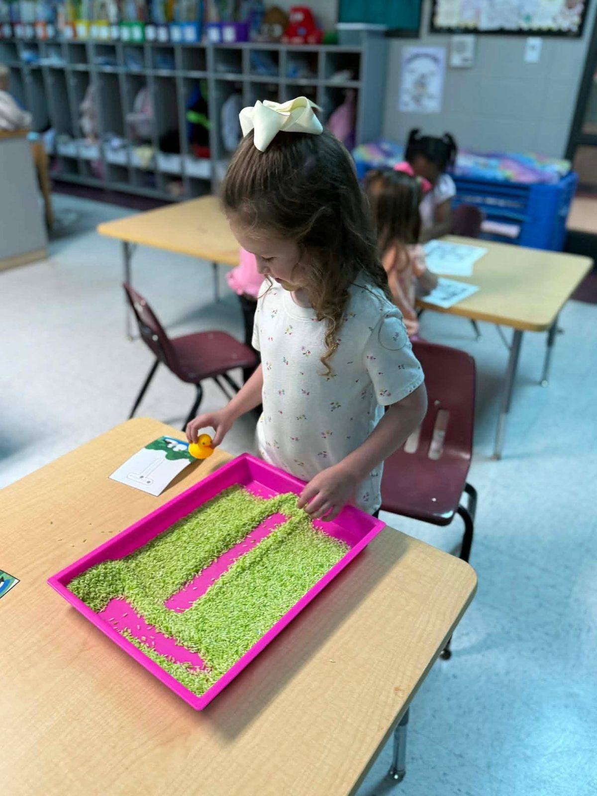 Preschooler practicing letters in a sensory tray