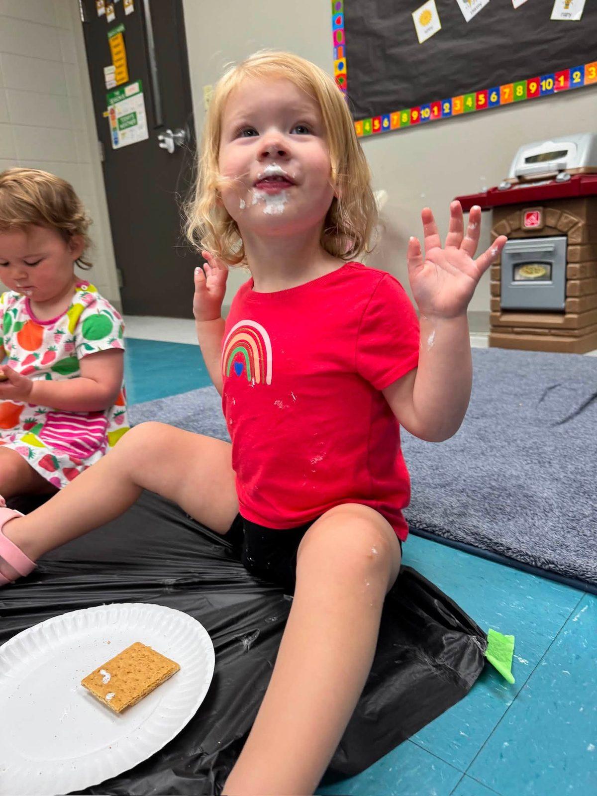 Happy KCCDC toddler waving at snack time